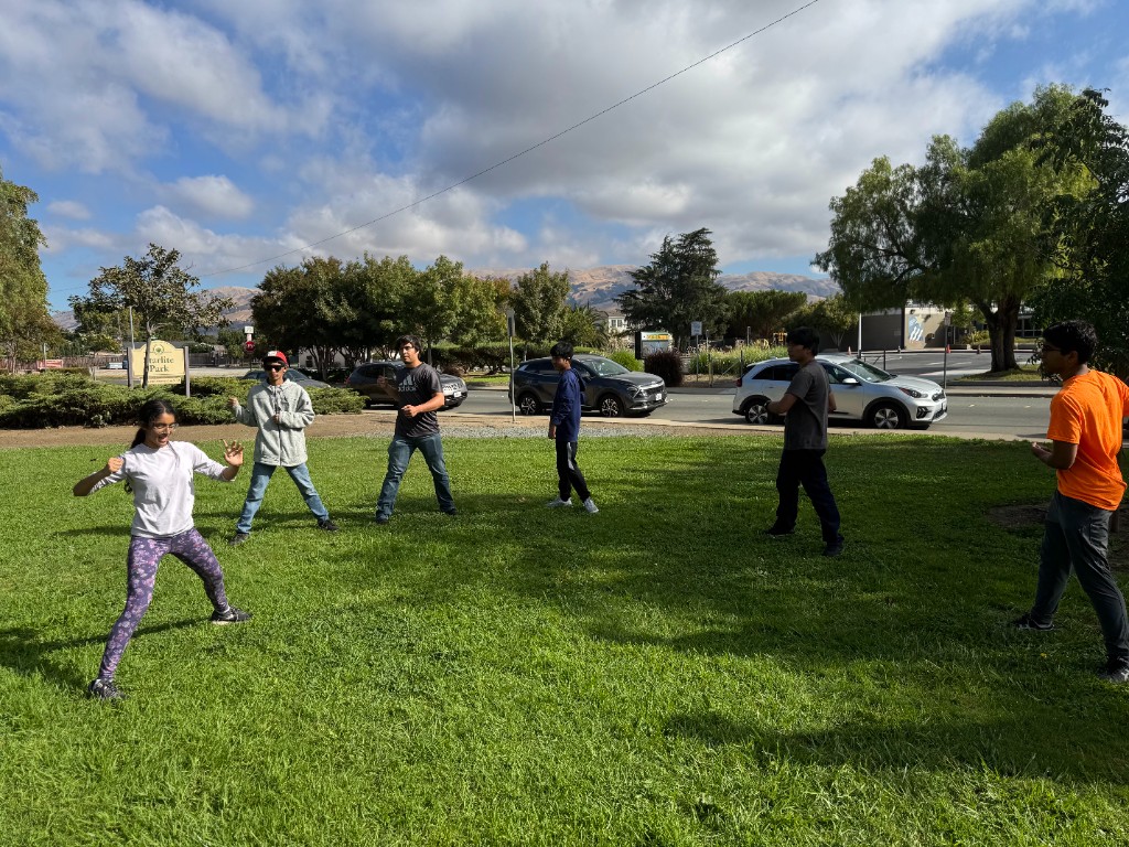 Teens and young adults practicing self-defense stances during an outdoor Brave Buds class in the park